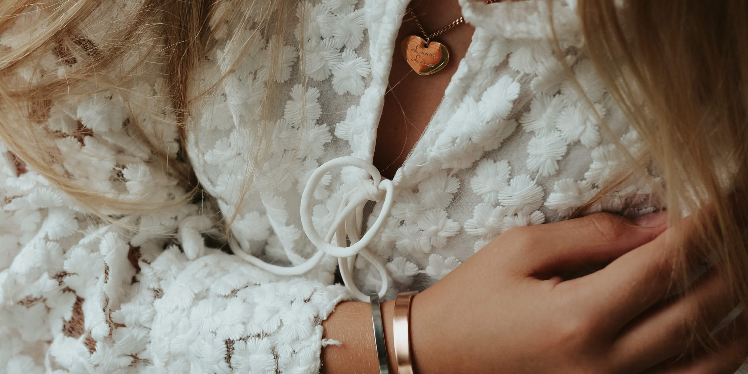 Image that has a pretty girl sitting by water showing bracelet